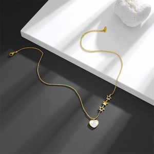 Golden heart shell necklace with three star charms on minimalist white platform display