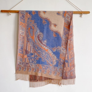 Blue and beige paisley pashmina shawl with fringes hanging on a wooden pole