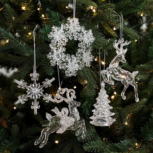 Set of clear acrylic Christmas ornaments with glitter reindeer and snowflake hanging on a tree