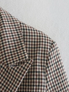 Detailed close-up of brown houndstooth pattern fabric on double-breasted blazer