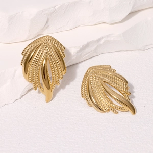 Minimalist golden wing textured stainless steel earrings on white decorative stone