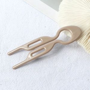 Detail of a brown U-shaped hair pin for buns with a smooth glossy resin finish