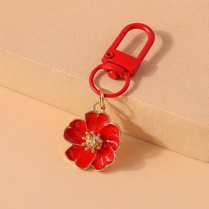 Macro view of red enamel flower keychain with gold trim and matching red lobster clasp