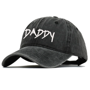 Macro shot of white DADDY embroidery on vintage washed dark grey baseball cap surface