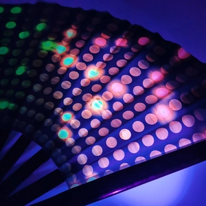 Macro shot of LED folding fan showing colorful light dots on dark fabric surface