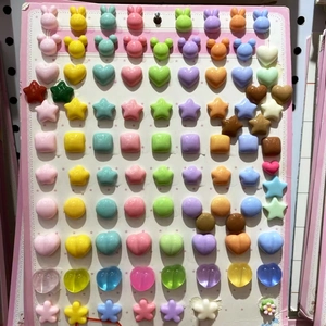 Close-up of assorted plastic stud earrings in heart and animal shapes on a pink display card