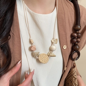 Close-up of bohemian pendant necklace with wooden geometric beads and woven rattan circle