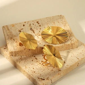Golden 18K plated stainless steel jewelry set with radial texture on a stone pedestal