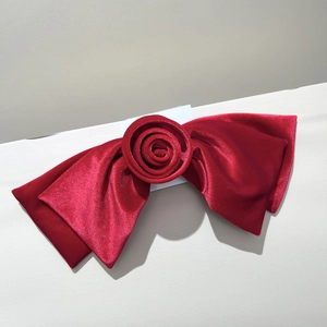 Détail d'une grande pince à cheveux en velours rouge avec rose et texture douce