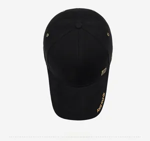 Detail of black baseball cap with gold embroidery and square metallic logo accent