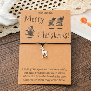 Close-up of Christmas deer charm bracelet on a wish card with dark wooden background