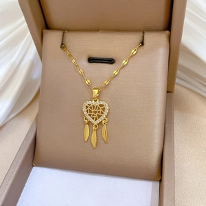 Dettaglio della collana acchiappasogni a cuore dorato con piume e zirconi incastonati
