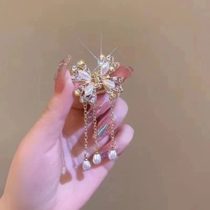 Detail of golden butterfly hair claw with white pearls and long hanging tassels