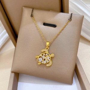 Macro shot of gold turtle necklace pendant inlaid with sparkling white zircons
