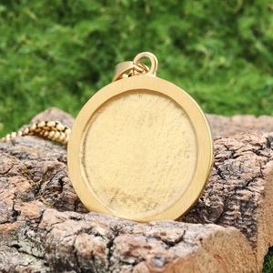 Vintage gold anchor coin pendant necklace on natural wood and moss background