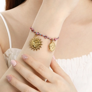 Detail shot of hand-woven colorful rope bracelet with celestial sun and moon gold charms