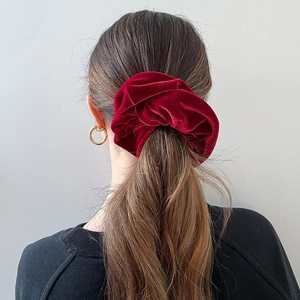 Close-up of a large burgundy velvet scrunchie showing soft texture and natural shine