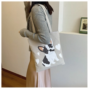 Detail of canvas tote bag with French Bulldog and white heart print worn by a model
