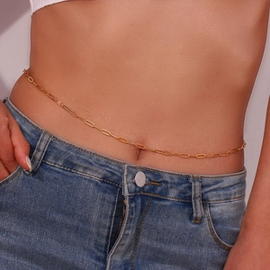 Detail van een minimalistische vergulde paperclip buikketting gedragen door een model