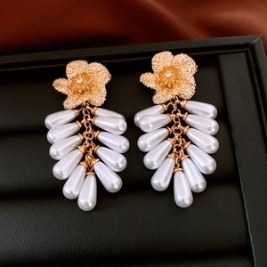 Detail of vintage gold flower earrings with matte texture and pearl tassel fringes