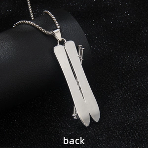 Back view of silver stainless steel ski and pole pendant necklace on black background