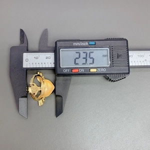 Macro view of 23.5 mm measurement of a gold plated red heart wing ring with calipers