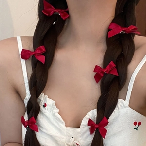 Detail showing red satin bow hair clips styled on a model's braided hair for a cute look