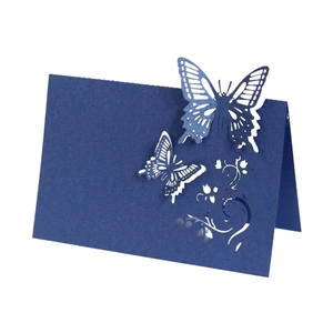 Deep blue laser-cut butterfly place card with intricate vine patterns on white background