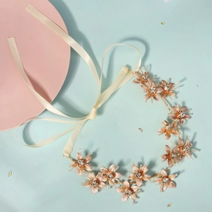 Detail of rose gold metal flower headband with rhinestones and off-white ribbons
