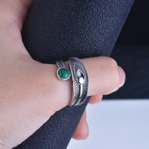Macro view of adjustable silver feather ring featuring a round green malachite stone