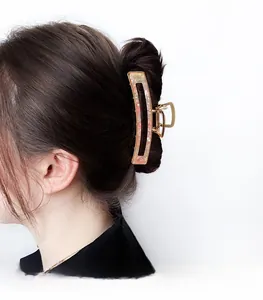 Detail of pink marble acetate hair claw clip with golden metal frame on blonde hair
