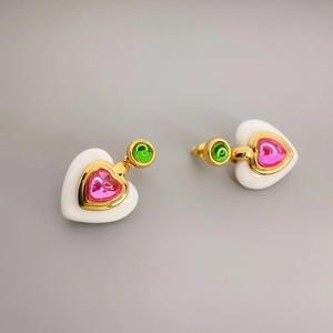 Close-up of heart-shaped earrings with pink gemstone, white resin, and gold edges