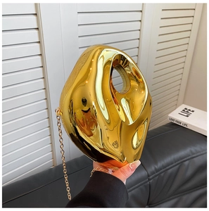 Close-up of a gold acrylic drop-shaped evening bag with a polished mirror finish