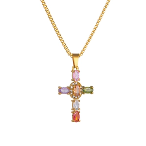 Golden cross necklace with colorful oval gemstones and cubic zirconia on white background