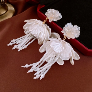 Detail of elegant white 3D flower earrings with bead tassels and gold connectors