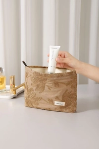 Detailed close-up of brown floral embroidery on a spacious cotton linen makeup bag