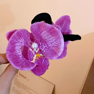 Detail of purple orchid hair claw clip with pearl center and black grip texture