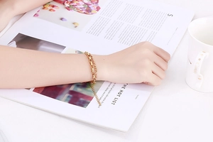 Detailed view of layered gold box and curb chains on a magazine with a white mug
