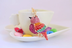 Detail of colorful kingfisher keychain with sparkling rhinestones on heart dish