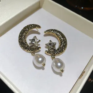 Elegant vintage moon and star earrings with diamonds and pearls in a white jewelry box