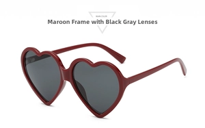 Close-up of heart-shaped dark red sunglasses with black lenses and metal hinges