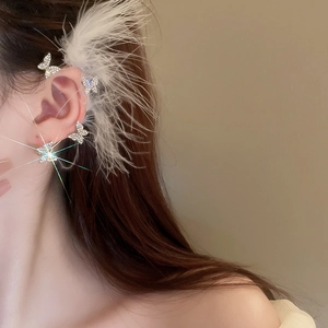 Detailed close-up of sparkling bow butterfly ear cuff with soft white feathers decoration