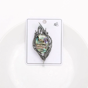 Close-up of feather brooch featuring iridescent abalone shell inlay and vintage metal work