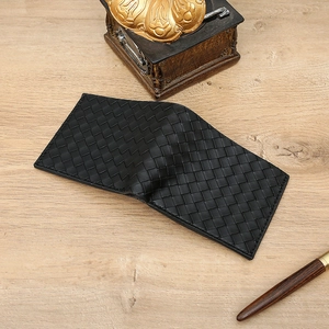 Detail of black woven leather wallet featuring card slots on a rustic wooden background