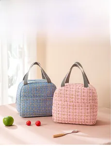 Detail of tweed insulated lunch bags in blue and pink with woven gold thread and striped handles