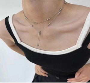 Detail of a layered silver bead tassel necklace worn on neck to show elegant fit