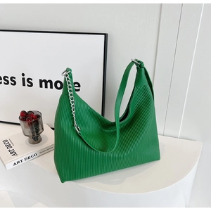 Détail du sac hobo plissé vert avec bandoulière chaîne argentée sur socle blanc