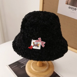 Détail d'un chapeau bob en polaire noire avec patch cœur et nœud à carreaux