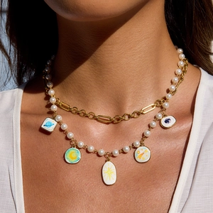 Gros plan d'un collier double rang en acier doré avec perle et pendentifs célestes