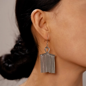 Close-up of long silver metallic tassel earrings worn by a model for a stylish look